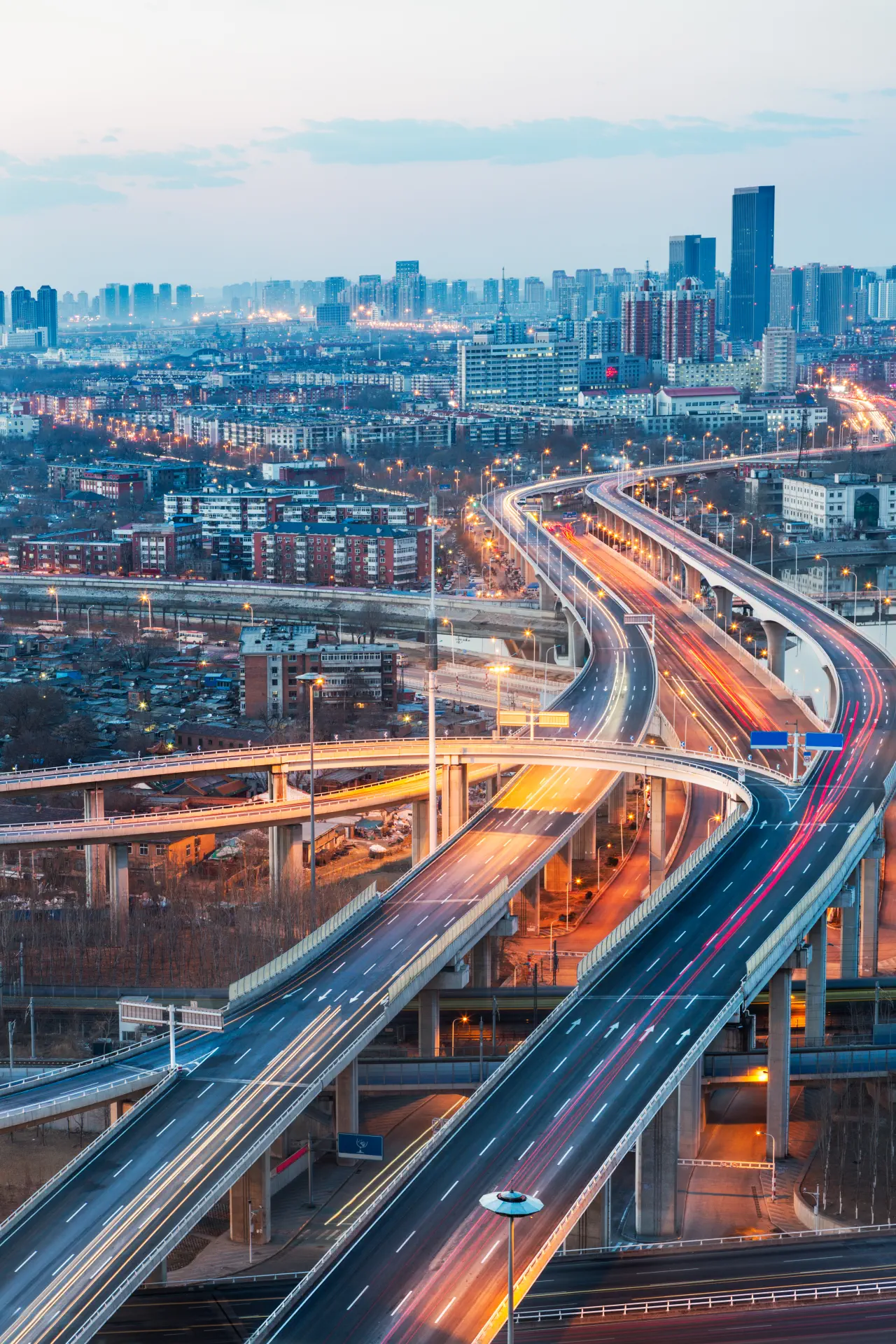 Geschwungene Stadtautobahn in der Abenddämmerung vor einer Großstadt-Skyline